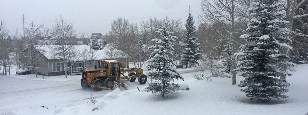 Crews plow a snowy winter road in the Blue Sage neighborhood